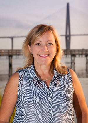 Smiling photo of Ellen standing on a dock near water